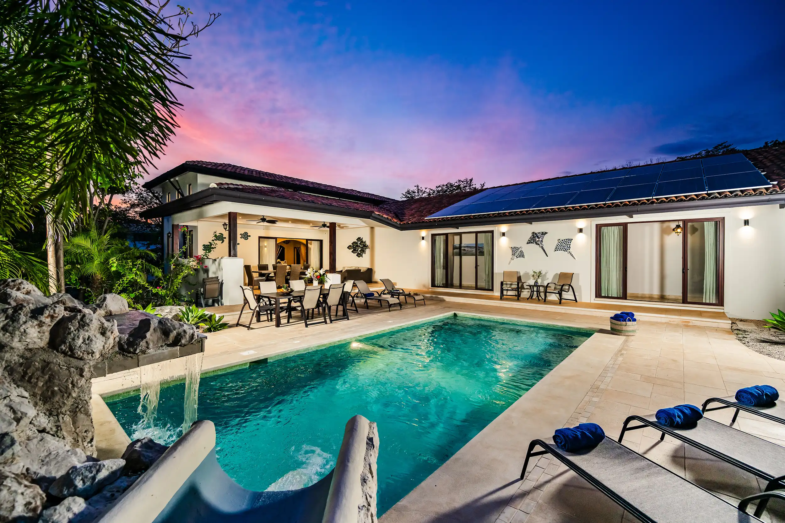 Piscina privada de Casa Bonita Beach iluminada al atardecer con jardines tropicales